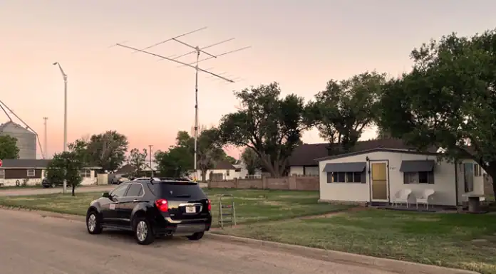 VHF Grid Activation — DM86 in Stratford Texas Black SUV parked on a residential street at sunset with a small house, trees, and a tall TV antenna nearby.